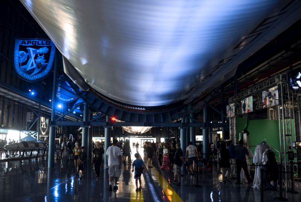 Kai and Kenny return down the length of the Saturn V, the second stage of which looms imposingly above them.